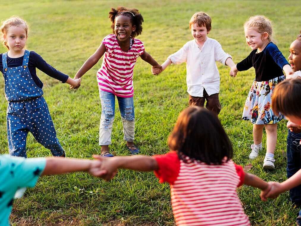 Eight children on the lawn holding hands in a circle for Zehnder sustainability